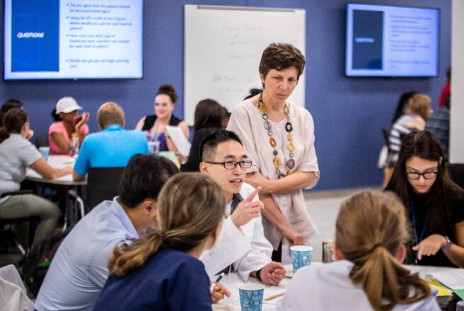 students working with college of medicine as professor looks on