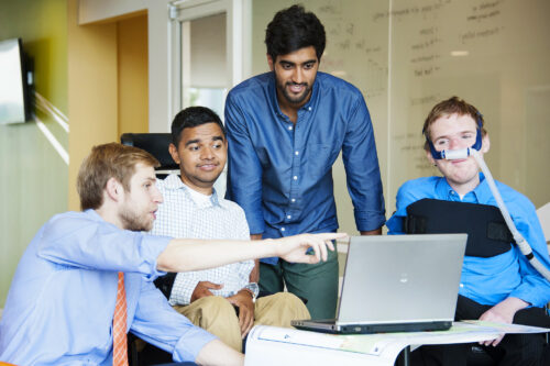 group of students look at laptop with instructor