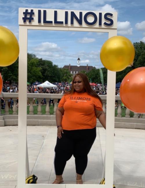 image of Jahnellia Brown standing by ILLINOIS sign on campus