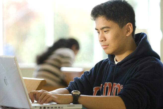 male wearing Illinois shirt using laptop