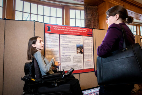 student presenting research poster to another person