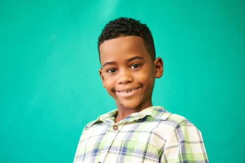 headshot of male youth smiling in front of green background