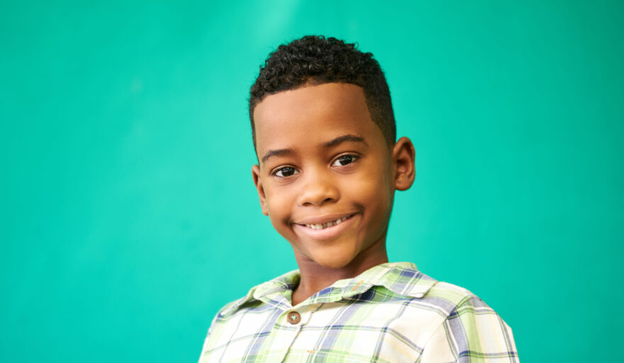 headshot of male youth smiling in front of green background