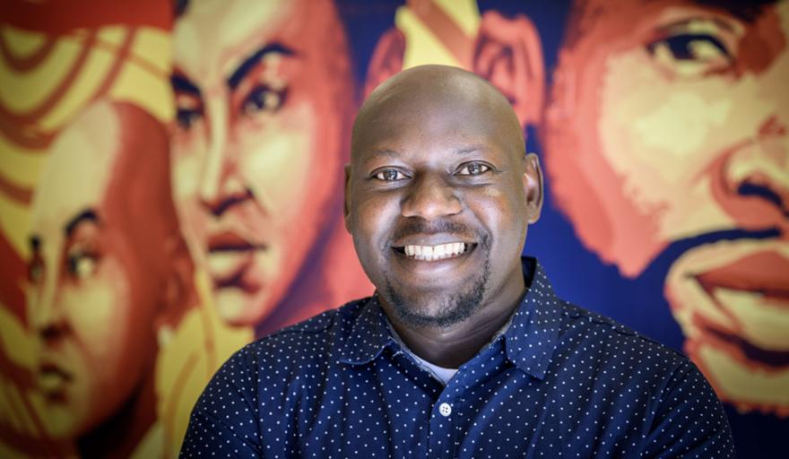 headshot of Moses Okum in front of mural