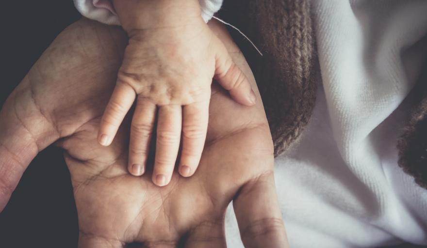 Baby hand placed on top of parents hand