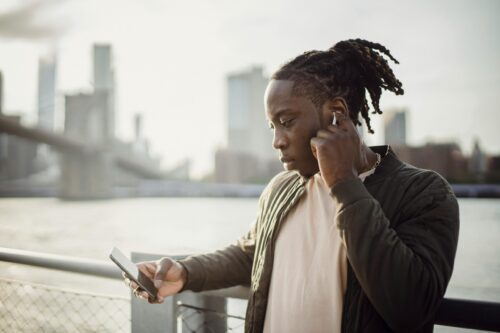 image of black male looking at phone in suburban area