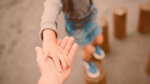 Child holding parents had as they step on pieces of wood