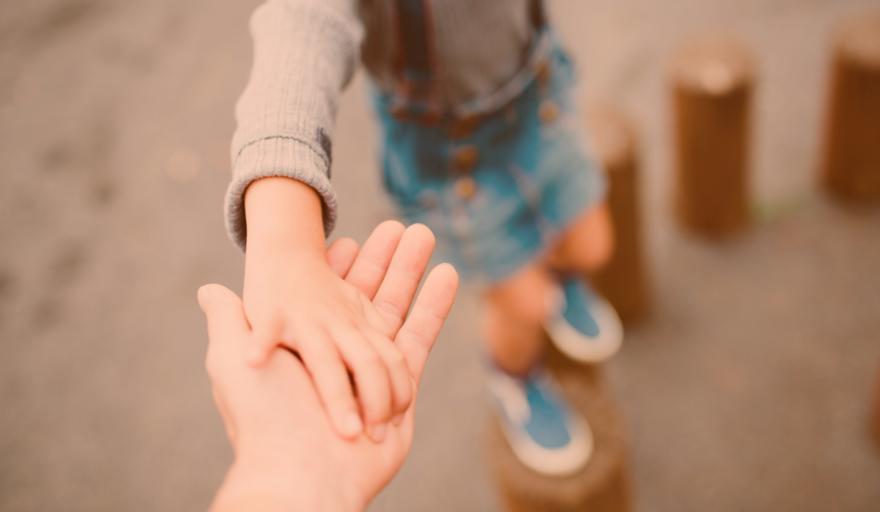 Child holding parents had as they step on pieces of wood