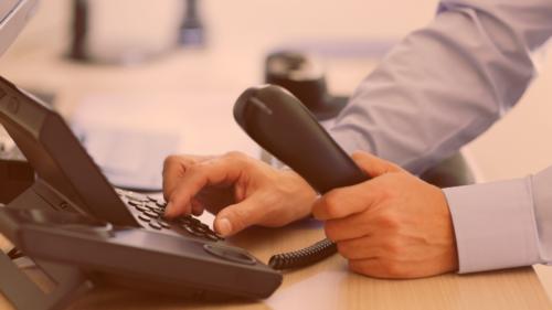 A person's hand dialing an office phone