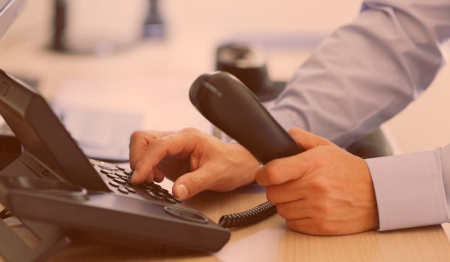 A person's hand dialing an office phone